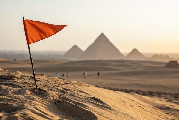 Orange marker flag on a desert ridge with the Giza pyramids, symbolizing Egypt payroll compliance